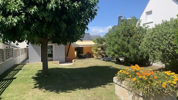 Relax in a serene setting surrounded by lush trees and vibrant flowers, with a patio area perfect for outdoor dining or relaxation.