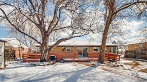 A two-story house with a covered porch, a garage, and a snow-covered yard. - The Meadowlark Manor Spacious Backyard & Hot Tub (Lakewood)
