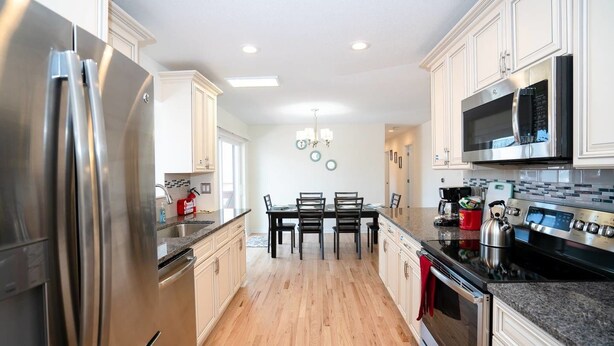 A modern kitchen with stainless steel appliances, a dining area with a table and chairs, and a microwave above the counter. - The Meadowlark Manor Spacious Backyard & Hot Tub (Lakewood)