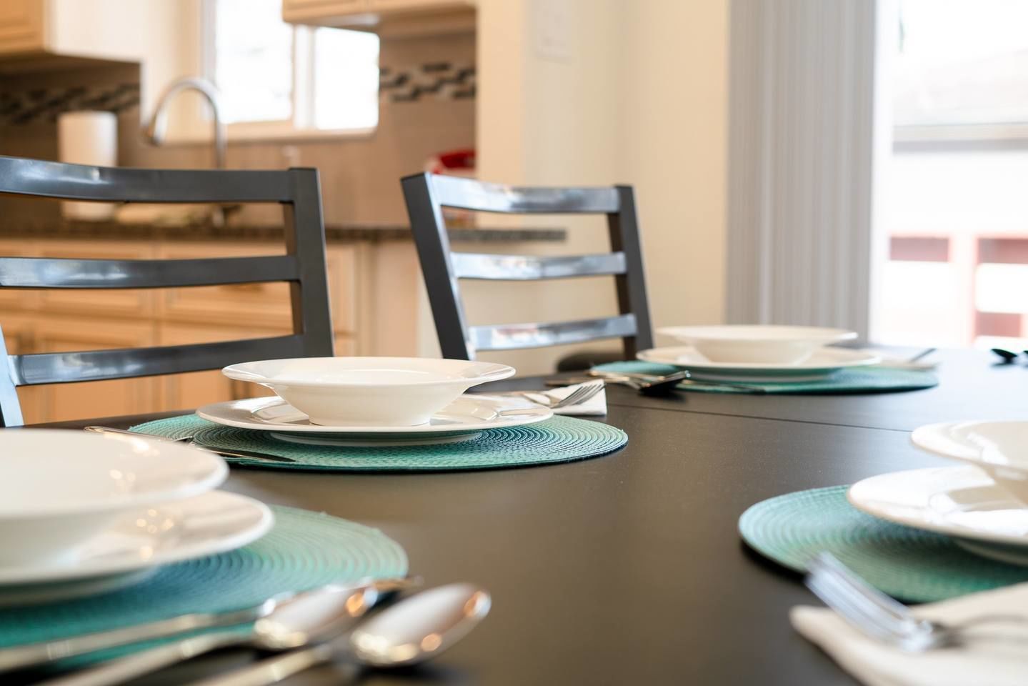 Een eettafel met servies, bestek en stoelen.