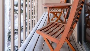 Une terrasse en bois avec une table et des chaises, donnant sur un paysage enneigé.