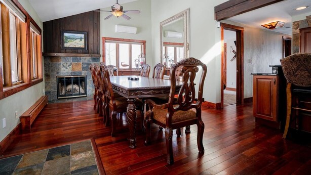 Un coin repas avec une table et des chaises en bois, une cheminée et un mur en pierre.