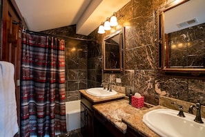 A bathroom with two sinks, a bathtub, and a shower curtain with a tribal pattern. - The Mountain Escape in Vail (Vail)