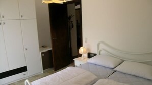Een slaapkamer met twee bedden, een nachtkastje met een lamp, een kledingkast en een spiegel.