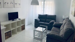 A modern living room with a grey sofa, a white coffee table, and a flat-screen TV on a white stand. - BEAUTIFUL APARTMENT IN PORTOSIN (porto do son)