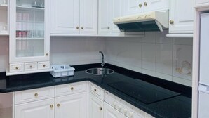 A kitchen with white cabinets, a black countertop, a stainless steel sink, and a built-in range hood. - BEAUTIFUL APARTMENT IN PORTOSIN (porto do son)