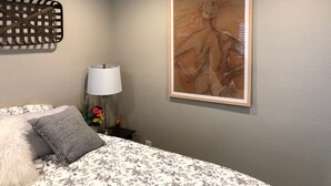 Une chambre à coucher avec un lit, une lampe, un tableau encadré et un ventilateur de plafond.