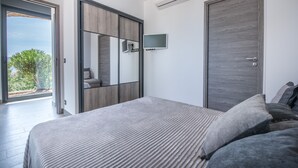 Ein Schlafzimmer mit Bett, Fernseher, Kleiderschrank und Tür.