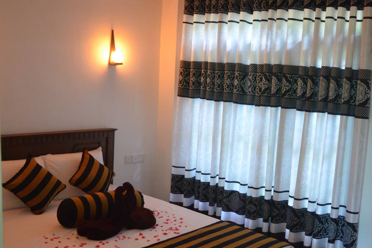 A neatly made bed with striped bedding, a bedside lamp, and a decorative pillow.