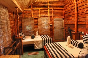 A cabin-style room with two beds, a wooden ceiling, and a small table.