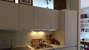 A kitchen with white cabinets, a gas stove, an oven, and a sink.