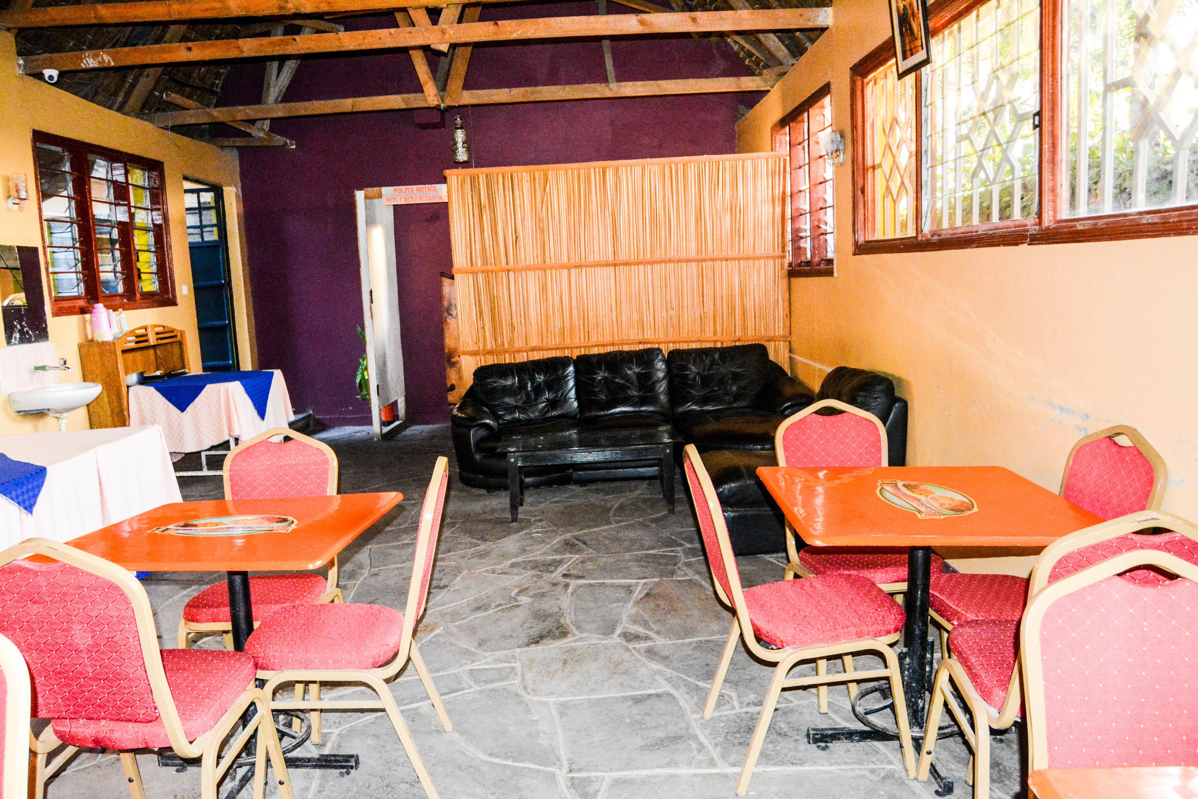 A restaurant with red and black furniture, stone flooring, and a purple wall.