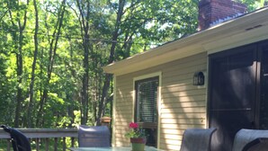 A deck with a table and chairs, surrounded by trees. - 4BR, 2 level, comfortable House In Kennebunkport/Cape Porpoise Maine.  (Kennebunkport)