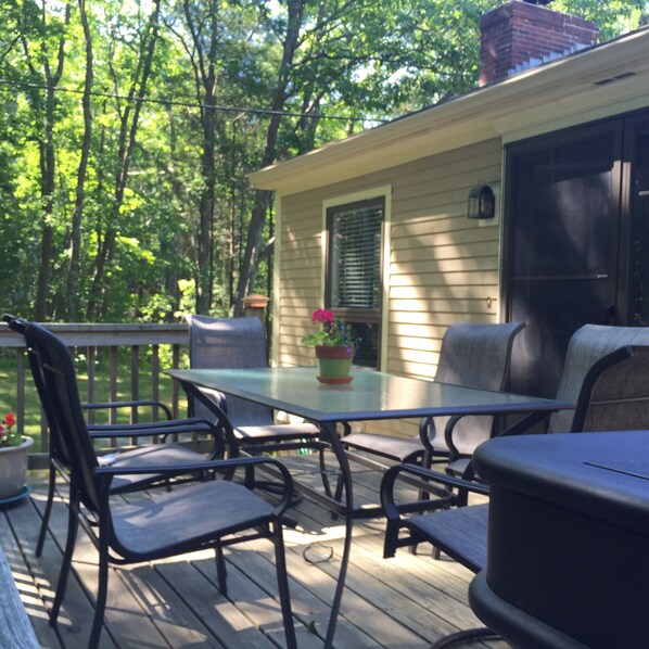A deck with a table and chairs, surrounded by trees.