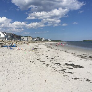 A sandy beach with houses in the background and a clear sky.