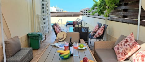 An outdoor patio with a table set for dining, a sofa, and a chair.