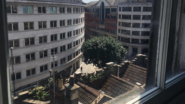 A view of a multi-story building with a curved facade, large windows, and a central courtyard with trees and a fountain. - The Mother Ruin (Bristol)