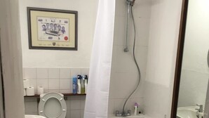 A bathroom with a toilet, sink, bathtub, and shower. There is a framed certificate on the wall, and toiletries are on a shelf. - The Mother Ruin (Bristol)