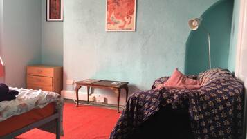 A bedroom with a bed, a nightstand, a dresser, and a poster on the wall.