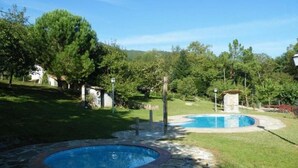 A backyard with two circular pools surrounded by stone pathways and lush greenery. - Allotjaments Colomer-Cullell (La Vall d'en Bas)