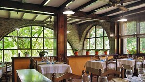 A restaurant with stone walls, arched windows, and wooden tables set for dining. - Allotjaments Colomer-Cullell (La Vall d'en Bas)