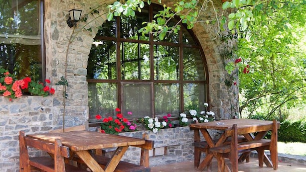 A rustic outdoor seating area with stone walls and wooden tables. - Allotjaments Colomer-Cullell (La Vall d'en Bas)