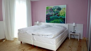 A bedroom with a bed, a nightstand, a painting, and a window with curtains. - Hotel Gasthof Goldener Adler (Horb am Neckar)