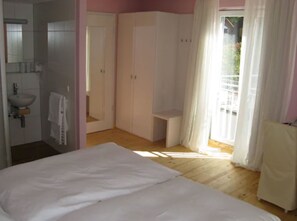 Une chambre à coucher avec un lit, une salle de bain avec un lavabo et une armoire.