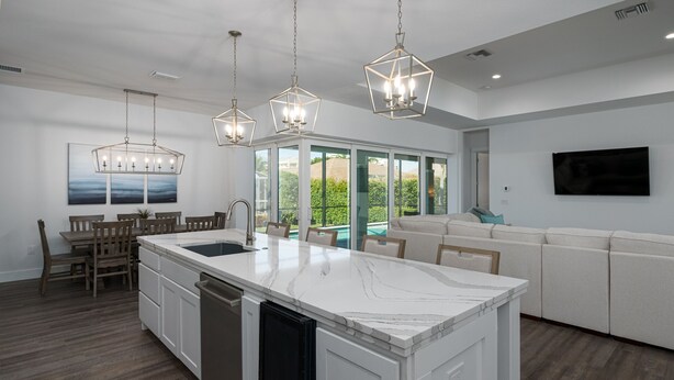 A modern kitchen with a central island, pendant lighting, a dining area, and a view of the outdoors. - 4 Bedroom, 4 Bathroom Custom Home with pool! 5 Min Walk to Beach! (Marco Island)