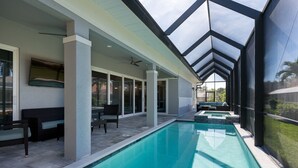 A modern outdoor pool area with a glass ceiling, seating, and a view of the surrounding landscape. - 4 Bedroom, 4 Bathroom Custom Home with pool! 5 Min Walk to Beach! (Marco Island)