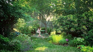 Un jardin agrémenté d’une table et de chaises, entouré d’une végétation luxuriante et de différentes espèces de plantes.