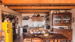 A rustic kitchen with wooden beams, a yellow refrigerator, and a dining table with chairs.