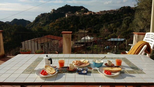 A table set for breakfast with a scenic view of a hillside village.