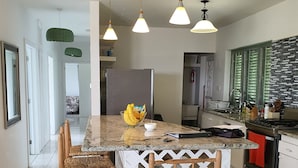 Una cocina moderna con una isla central, sillas de madera e iluminación colgante.
