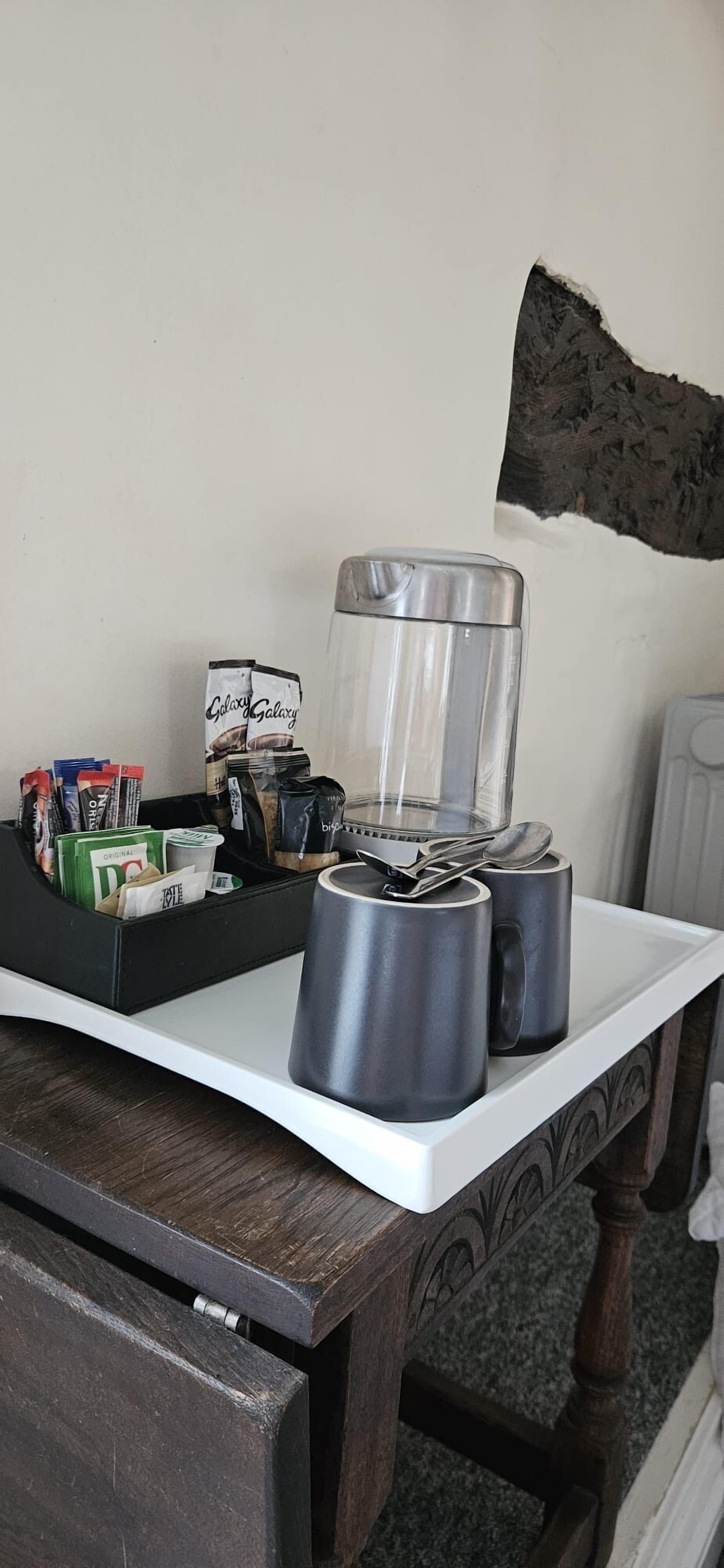 Una encimera de cocina con una cafetera, dos tazas y un paquete de café.