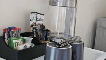 Un comptoir de cuisine avec une machine à café, deux tasses et un paquet de café.