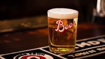 Et glas øl med teksten "Beer" på, stående på en underkop med logo og tekst.