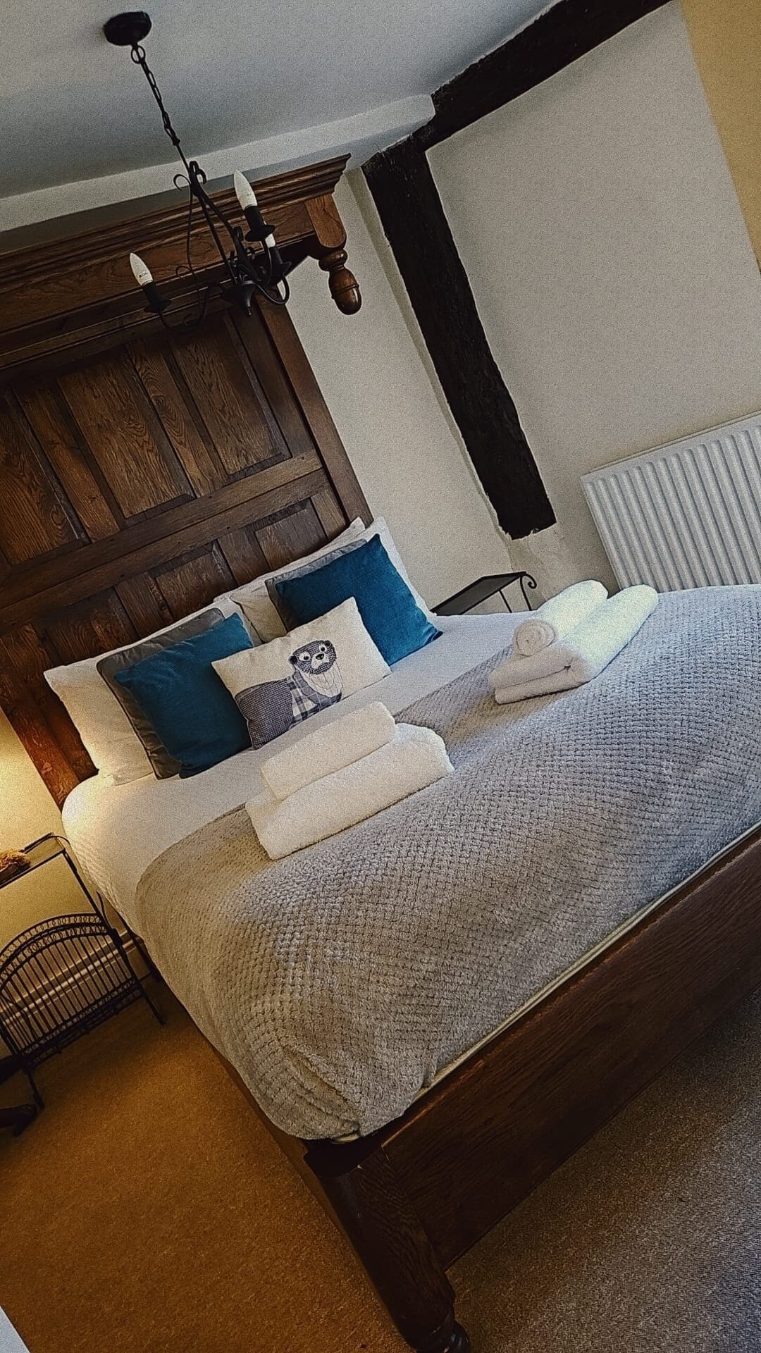 A bedroom with a wooden bed frame, a nightstand, a lamp, and a radiator.