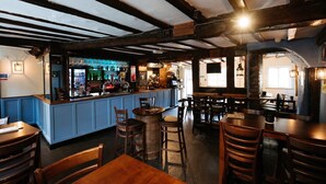 A bar area with wooden beams, a counter with bottles, and seating. - Cromwell's Tap House (Shrewsbury)