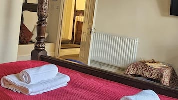 Habitación de hotel con una cama grande, cabecero de madera, candelabro y un espejo que refleja la habitación.