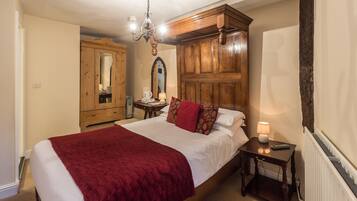 A bedroom with a large bed, wooden wardrobe, and a chandelier.