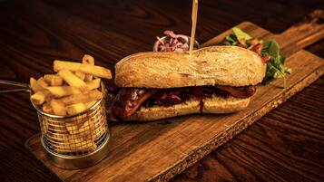 A sandwich on a wooden board with fries and a salad.