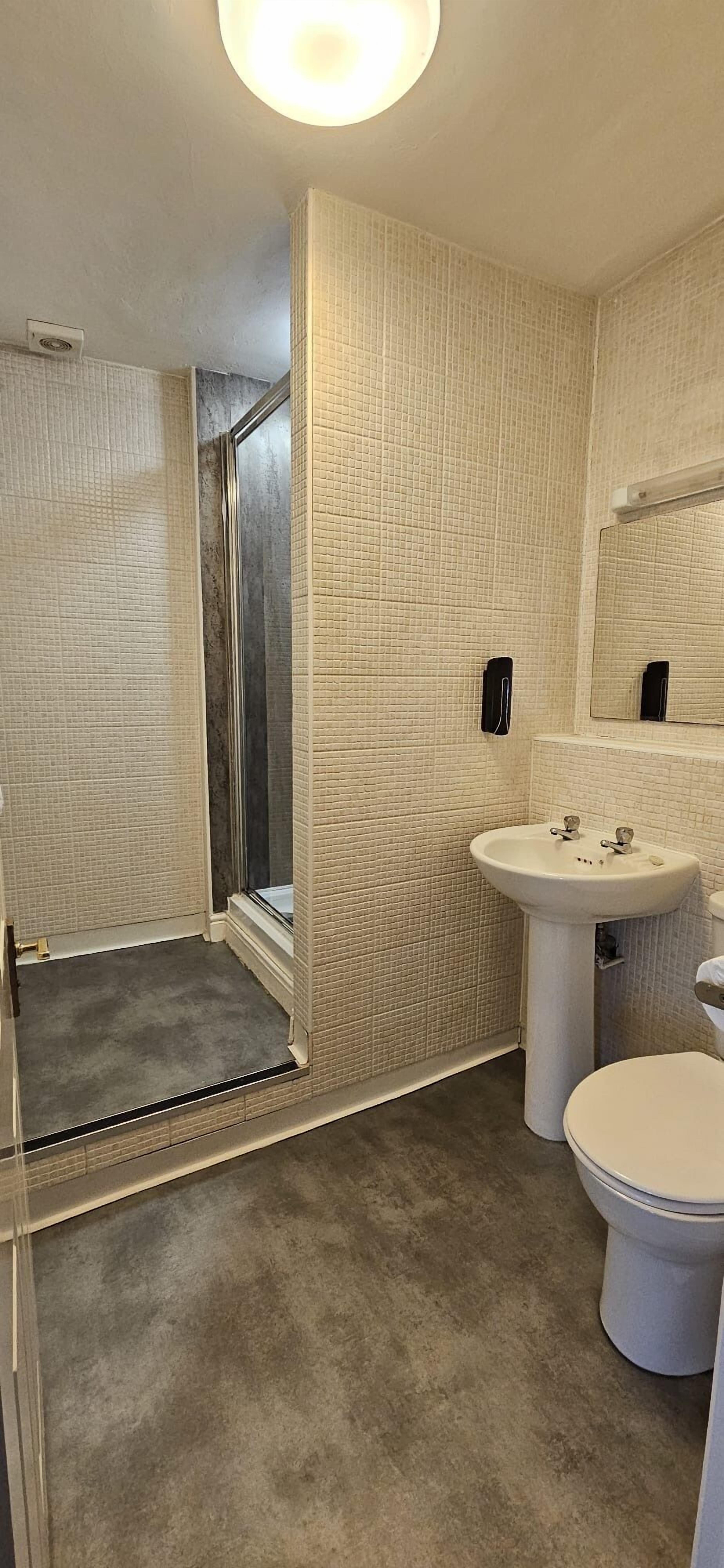 A bathroom with a shower, sink, and toilet.