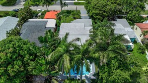 Vista aérea de una zona residencial con casas, una piscina y palmeras.