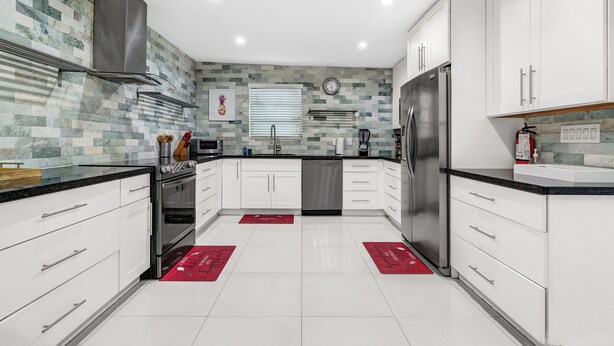 Una cocina moderna con armarios blancos, electrodomésticos de acero inoxidable y un salpicadero de azulejos.