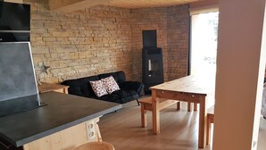 A modern kitchen with a wooden countertop, a black stove, and a stone wall. - Apartment BOUQUETIN in new chalet with view of Lake Matemale sleeps 8 (Les Angles)