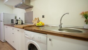 Een kleine keuken met een wasmachine, een magnetron en een spoelbak.