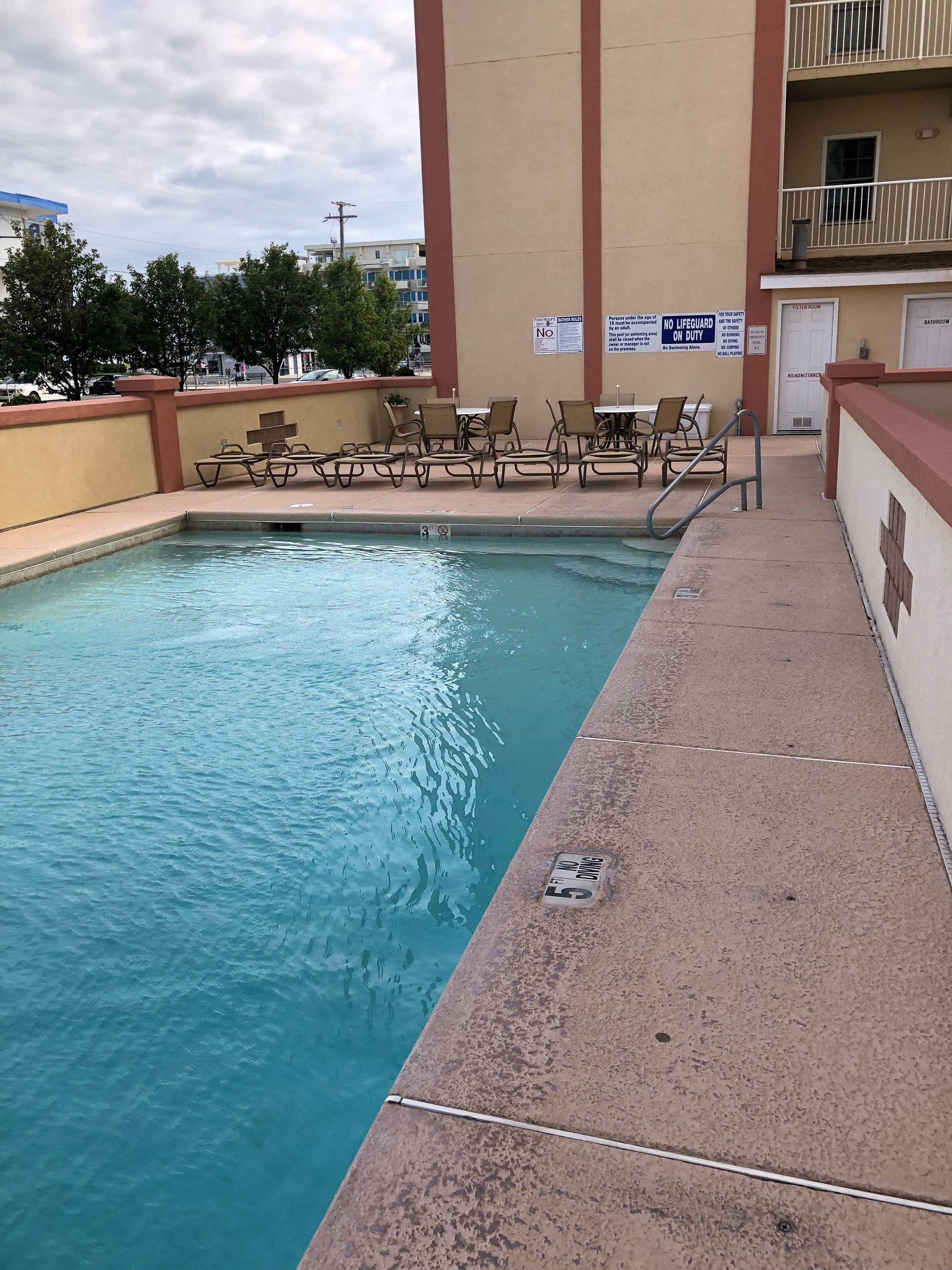 A swimming pool with lounge chairs and a no diving sign.