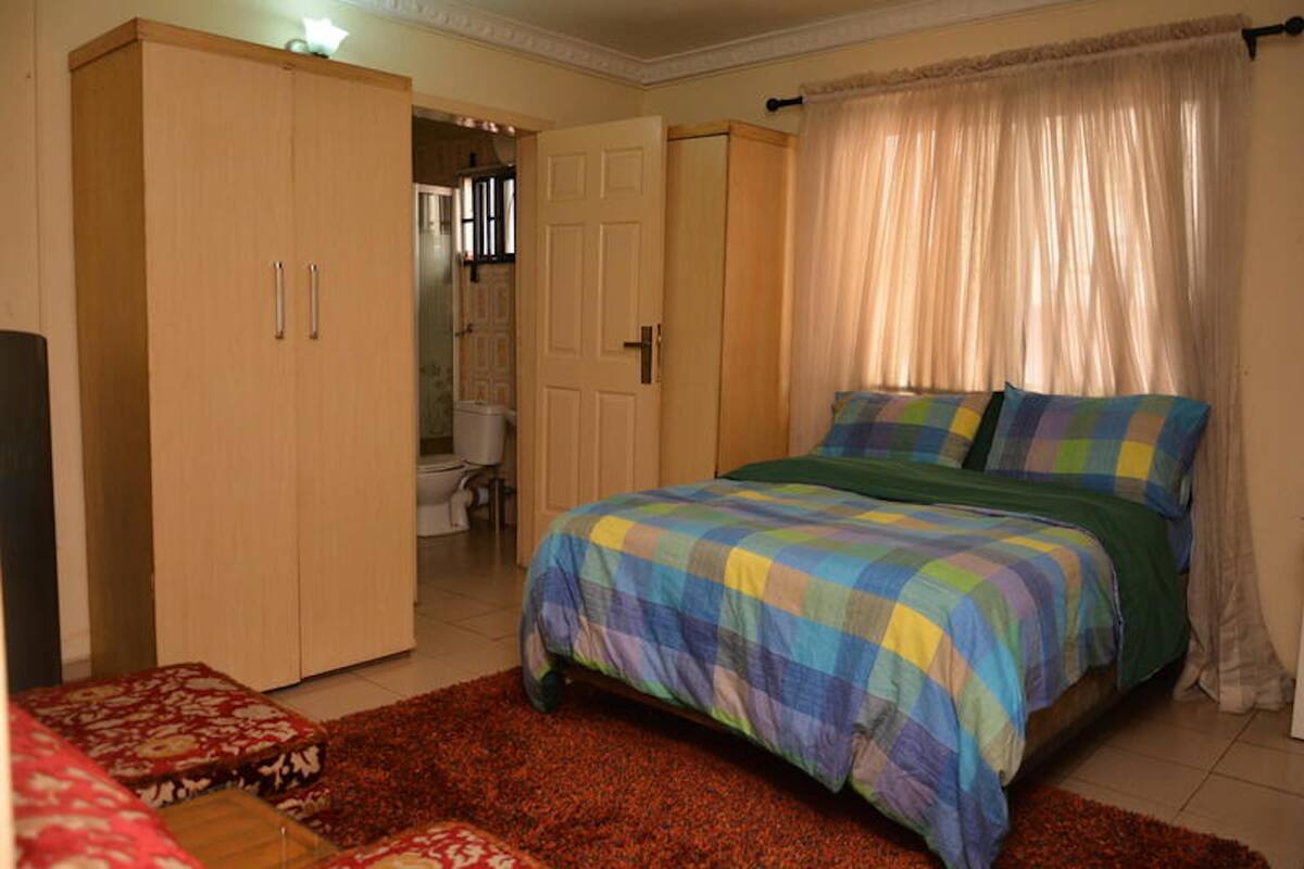 A bedroom with a bed, a wardrobe, a bathroom, and a red carpet.
