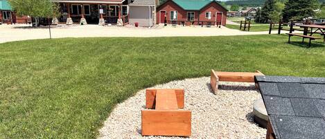 A lodge with a large lawn, outdoor seating, and a mountain view.